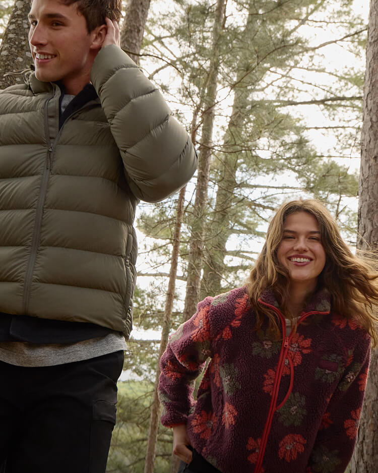 Two models wearing new seasonal Roots styles while canoeing on a lake.