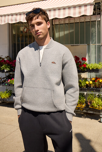 Man wearing a grey ribbed collar quarter zip and dark sweatpants.