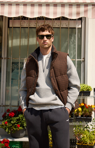 Man wearing a padded vest, quarter zip and dark sweatpants.