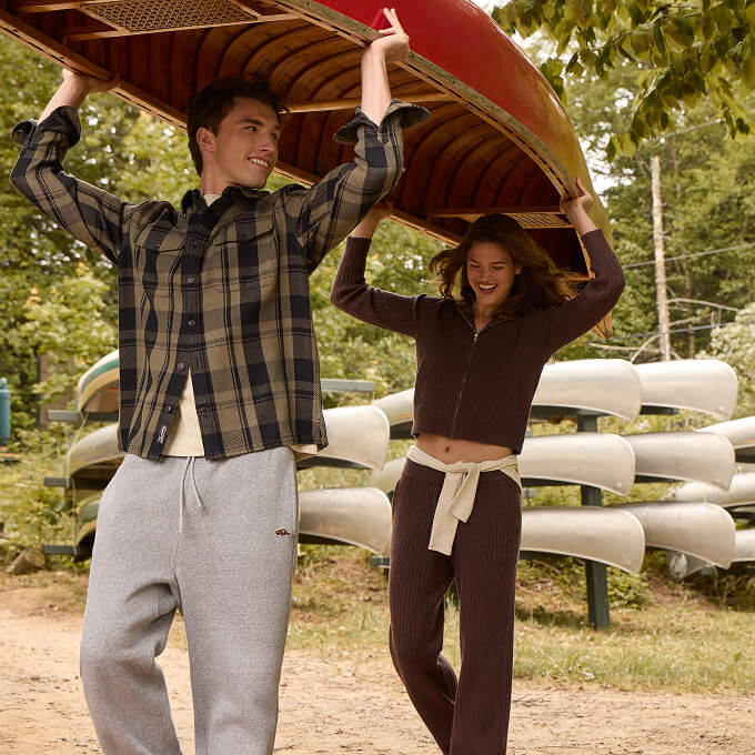 Man and woman carrying a canoe in layered fall styles.
