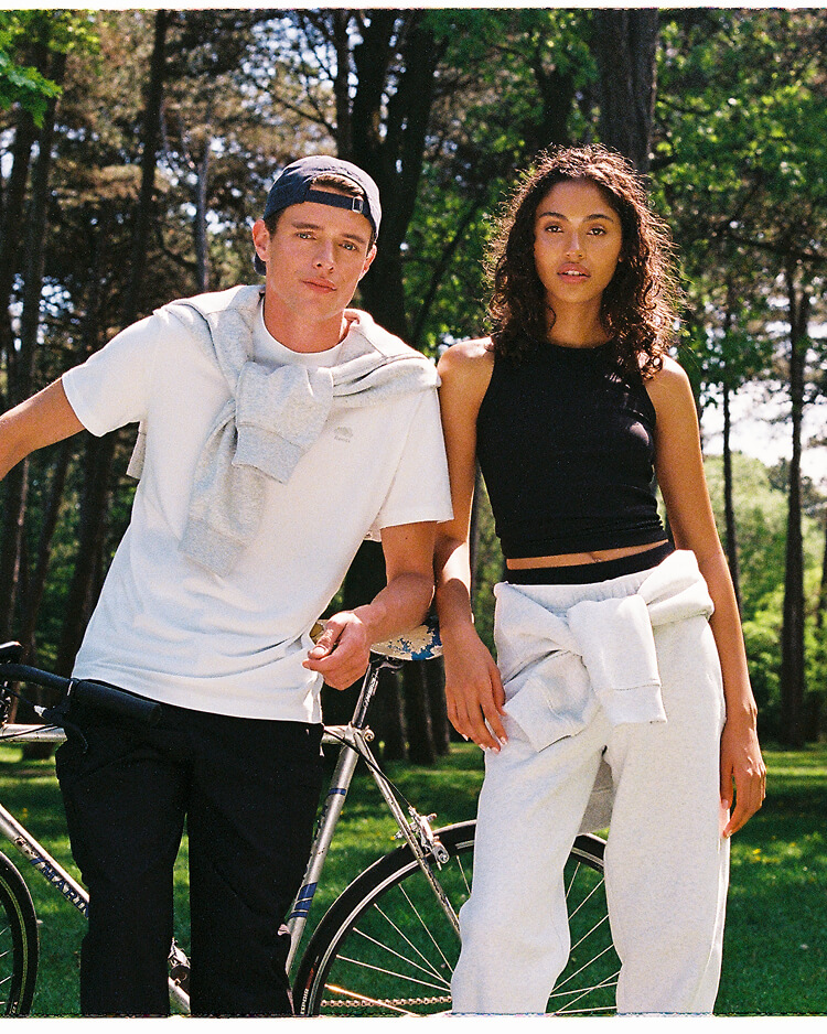 Two models wearing activewear outdoors with a bicycle.