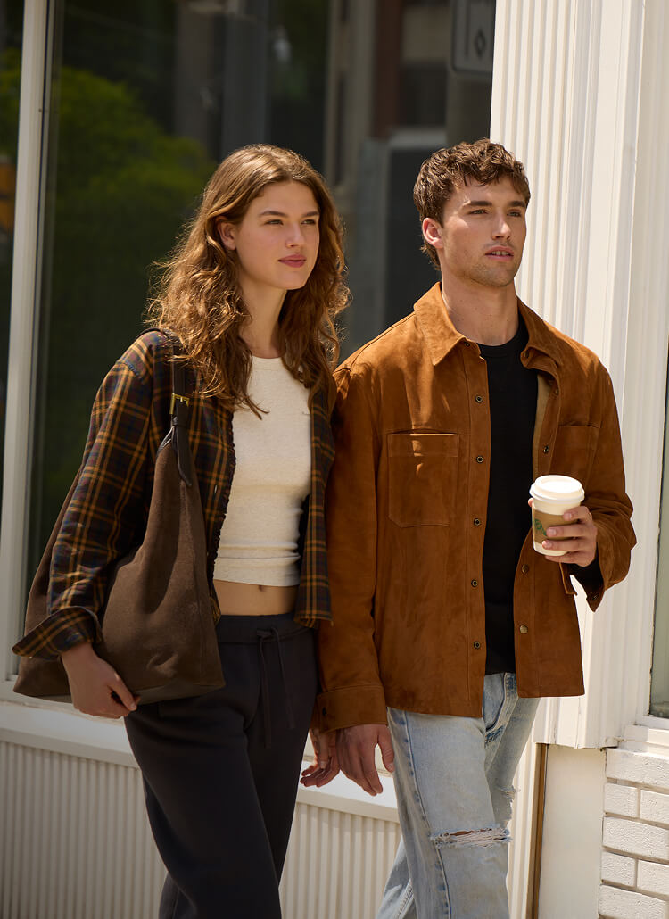Woman and man wearing layered Roots fall styles outside a shop.